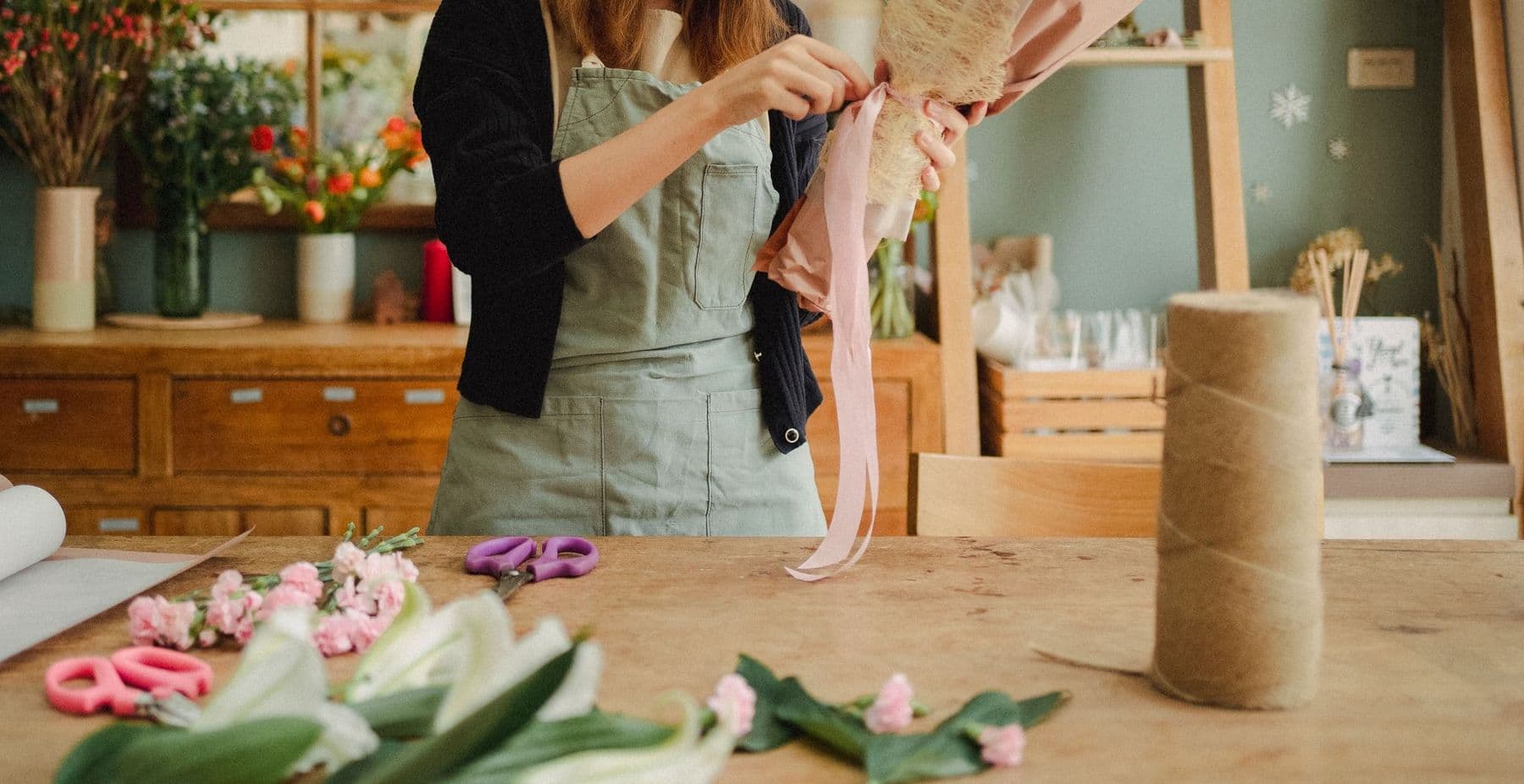 Florist cutting ribbon at the wrapping bench