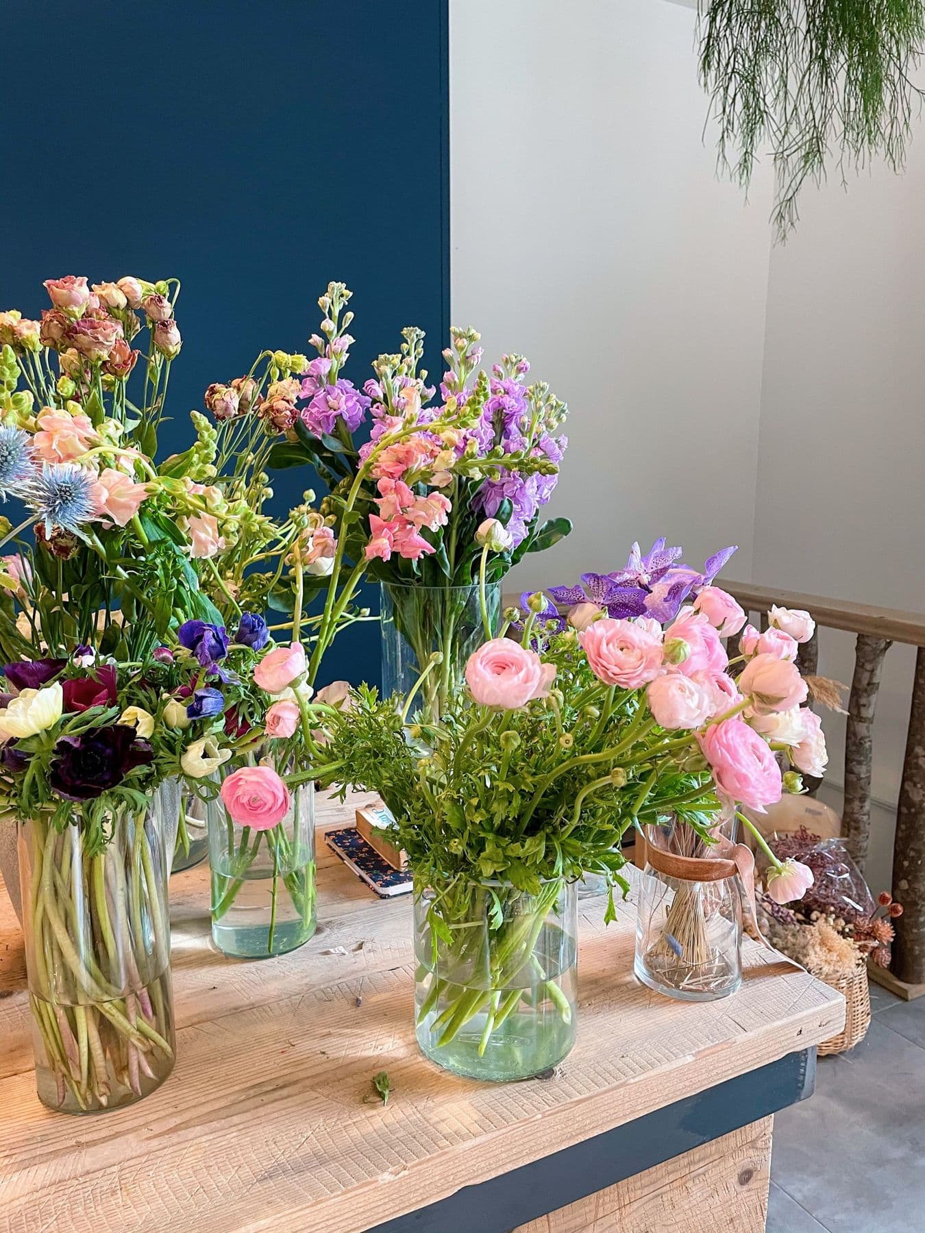 Jugs of mixed stocks, sweet peas and roses on a wooden shop counter