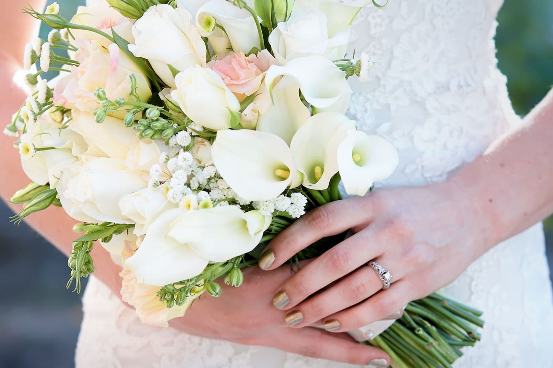 Bride holding a bouquet of white calla lilies and roses