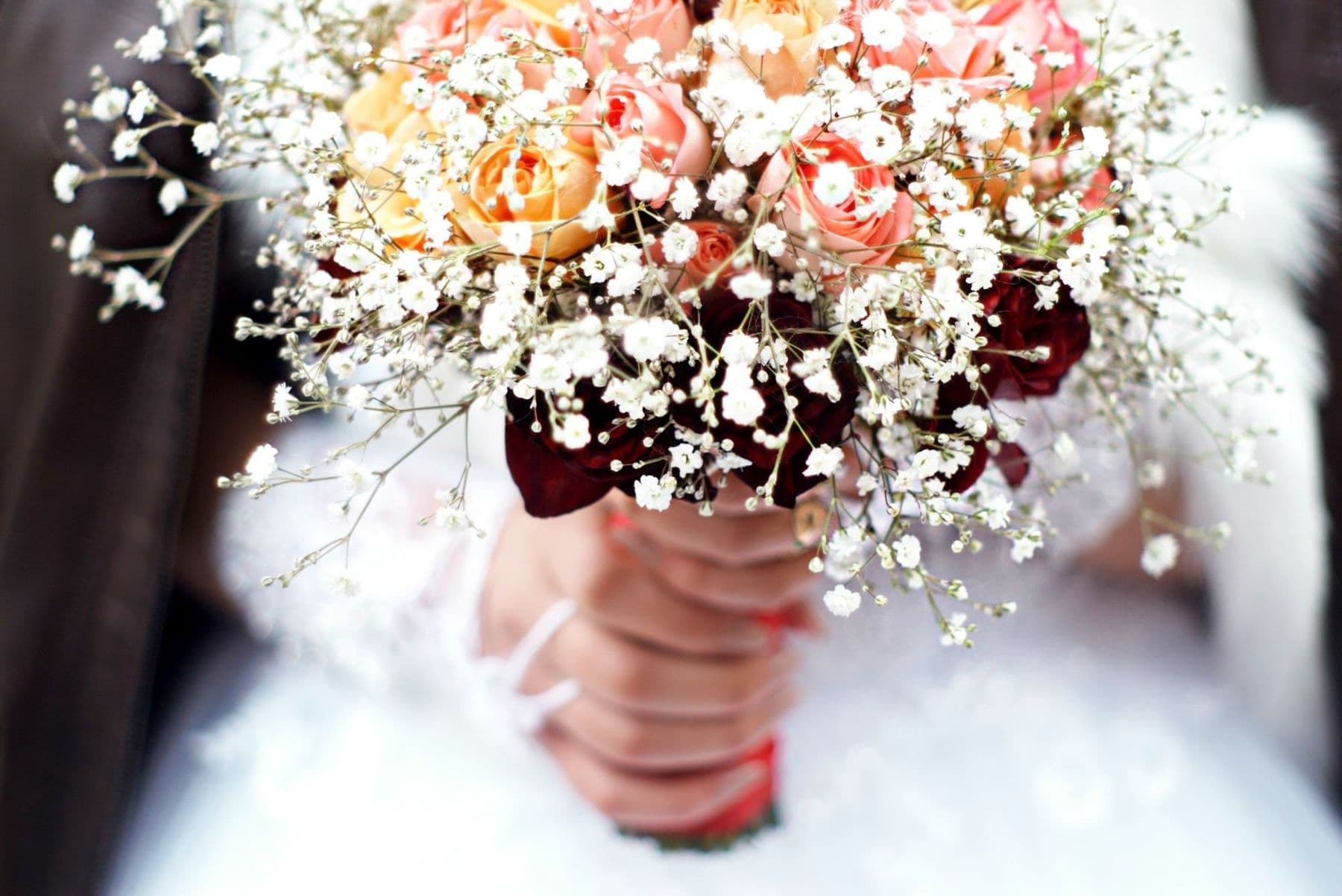 Bridal bouquet of peach roses wrapped in a cloud of gypsophila
