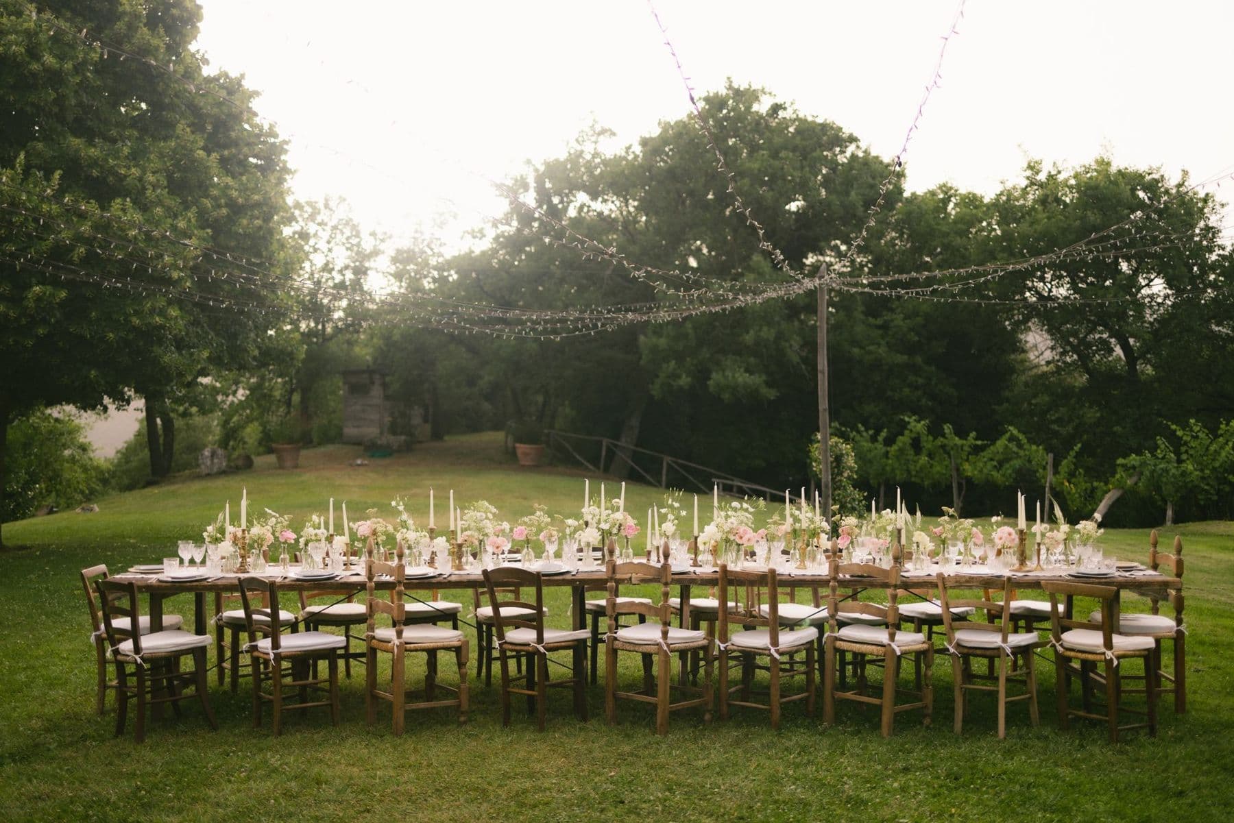 Long outdoor wedding table on a lawn, dressed with flowers